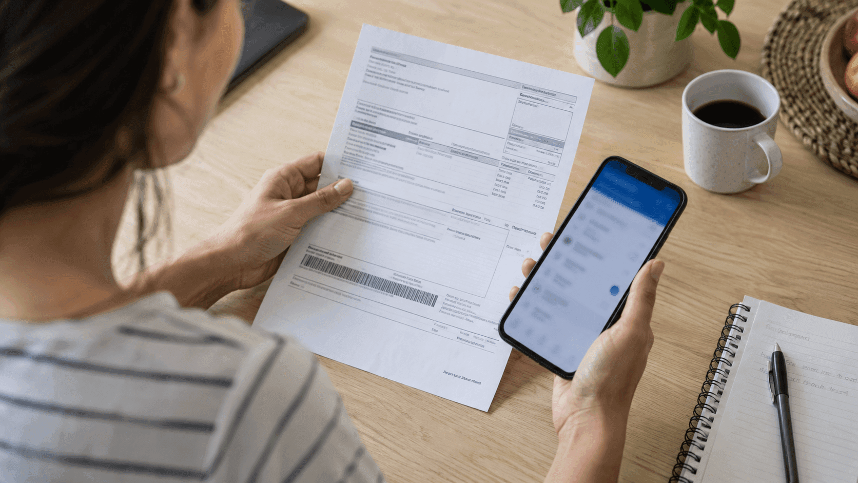 Pessoa conferindo um boleto em papel e as informações de pagamento no celular.